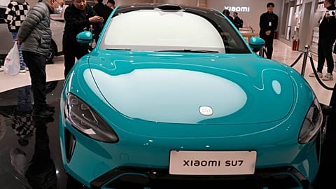 Visitors to the Xiaomi Automobile flagship store look at the Xiaomi SU7 electric car on display in Beijing, Tuesday, March 26, 2024.