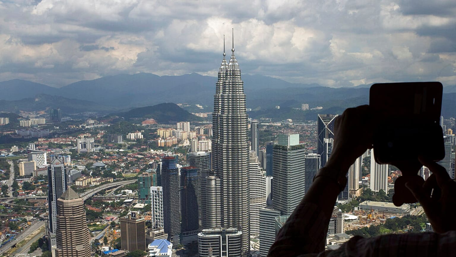 Petronas Kuleleri'nden Kuala Lumpur'un fotoğrafını çeken bir kişi 