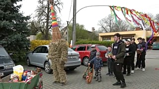 Участники шествия и наряженный в соломенный костюм Иуды местный школьник