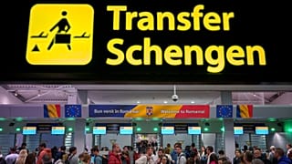 Passengers arriving at the Henri Coanda International Airport pass under a Schengen Information sign, in Otopeni, near Bucharest, Romania, Sunday, March 31, 2024.