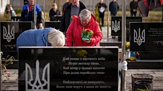 Trauernde Angehörige an einem Grab in Butscha.
