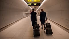 Flight attendants arriving at the Henri Coanda International Airport pass under a Schengen Information sign, in Otopeni, near Bucharest, Romania, Sunday, March 31, 2024. 
