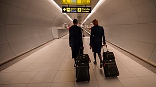 Flight attendants arriving at the Henri Coanda International Airport pass under a Schengen Information sign, in Otopeni, near Bucharest, Romania, Sunday, March 31, 2024.