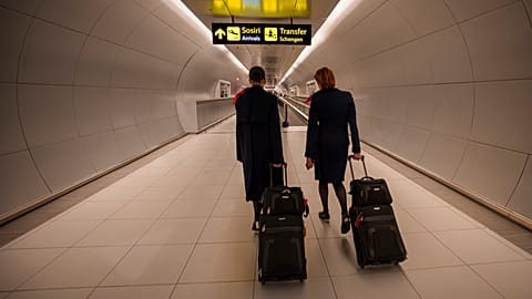 Flight attendants arriving at the Henri Coanda International Airport pass under a Schengen Information sign, in Otopeni, near Bucharest, Romania, Sunday, March 31, 2024. 