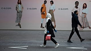 In this Monday, May 11, 2020 file photo, a woman and man walk past each other on a main shopping street in Antwerp, Belgium. 
