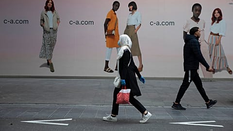 In this Monday, May 11, 2020 file photo, a woman and man walk past each other on a main shopping street in Antwerp, Belgium. 