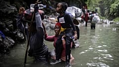 Migrantes haitianos caminan por el agua mientras cruzan el Tapón del Darién desde Colombia a Panamá con la esperanza de llegar a Estados Unidos, el 9 de mayo de 2023.
