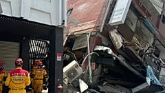 In this photo released by the National Fire Agency, members of a search and rescue team prepare outside a leaning building in the aftermath of an earthquake in Hualien.