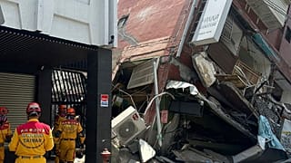 In this photo released by the National Fire Agency, members of a search and rescue team prepare outside a leaning building in the aftermath of an earthquake in Hualien.