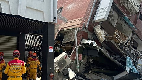 In this photo released by the National Fire Agency, members of a search and rescue team prepare outside a leaning building in the aftermath of an earthquake in Hualien.