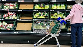 A shopper faces partly empty shelves in a supermarket in London, Thursday, Sept. 30, 2021.