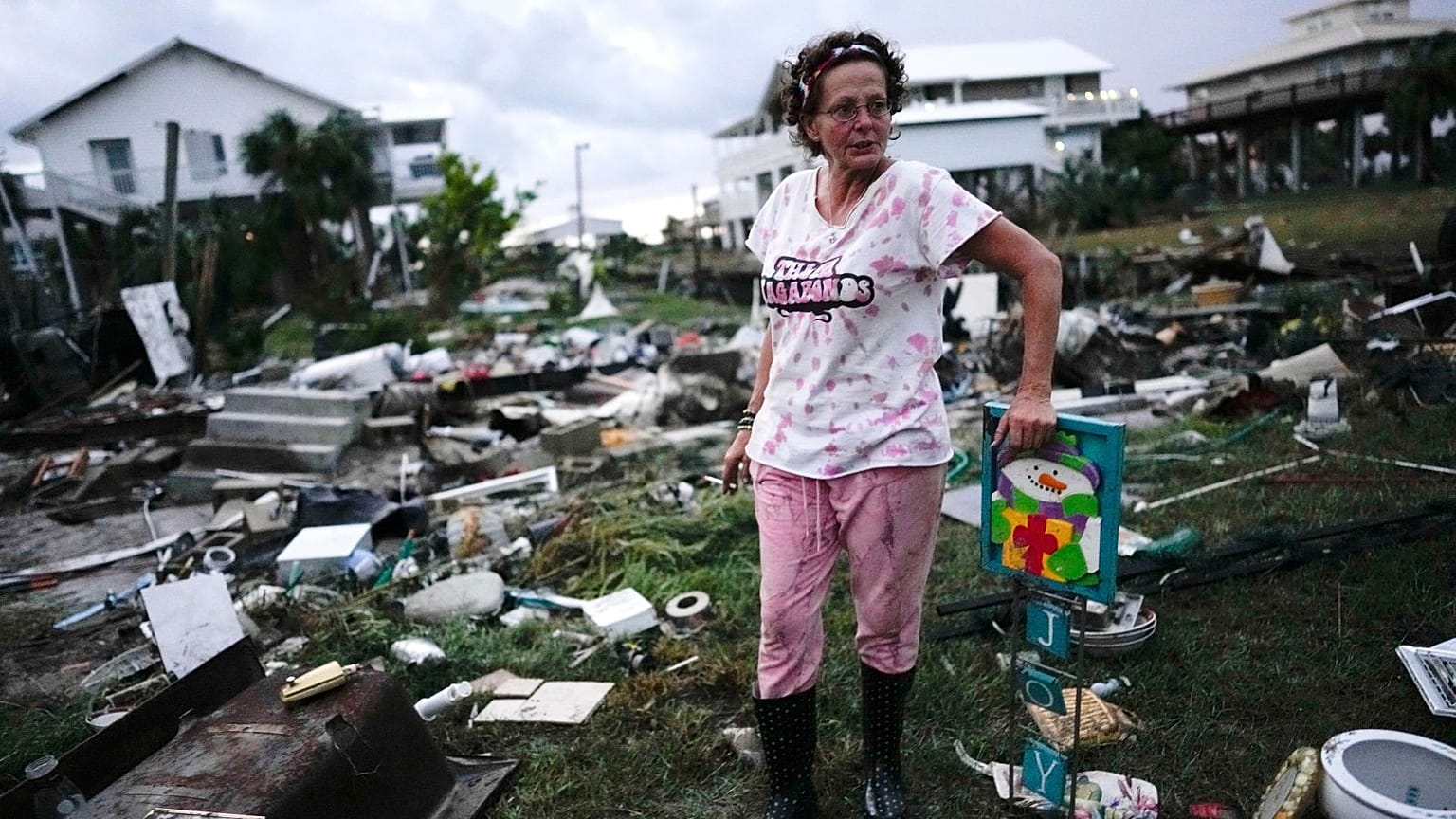 A woman stands beside the wreckage of her mother's home in Horseshoe Beach, Florida, hit by Hurricane Idalia in late August 2023.