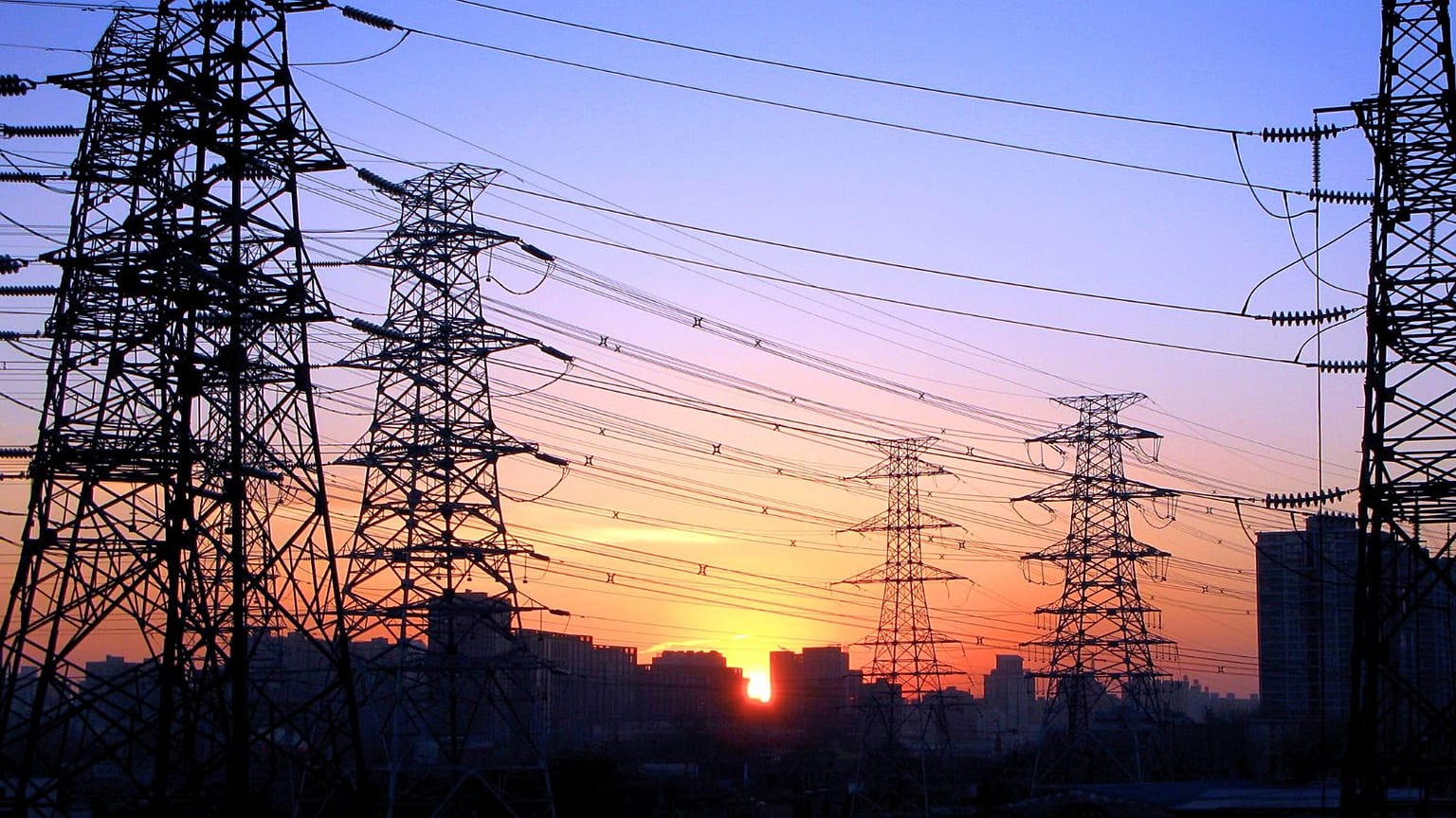 El sol se pone entre líneas eléctricas en Pekín, China.