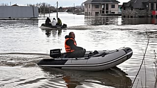 People use rubber boats in the flooded street after part of a dam burst, in Orsk, Russia. State media say Russia's government has declared the situation in flood-hit areas in 