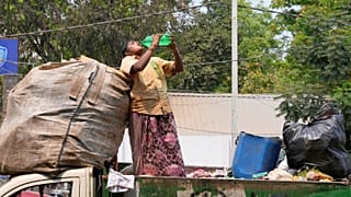 Une éboueuse se désaltère debout sur un camion par une chaude journée à Hyderabad, en Inde, le 12 mars 2024.
