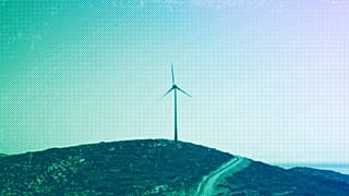 A road leads past a wind turbine stands on the Aegean island of Tilos, August 2018