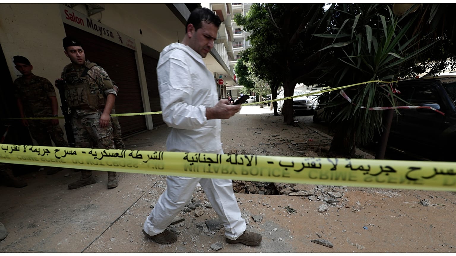 محقق من الجيش اللبناني يتفقد هاتفه المحمول خارج المبنى الذي اندلعت فيه الاشتباكات بين القوات اللبنانية وعضو سابق في تنظيم الدولة الإسلامية_ طرابلس
