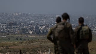 جنود إسرائيليون يقفون بالقرب من الحدود بين إسرائيل وغزة وينظرون إلى المباني المدمرة في القطاع