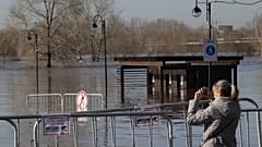 A woman takes a photo of a flooded area next to Ural river in Orenburg, Russia.