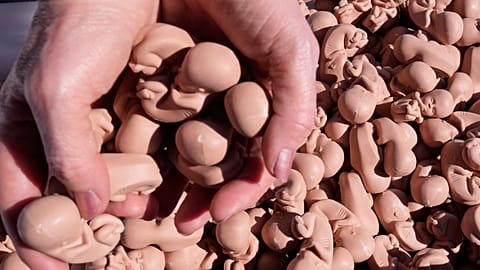 Egy abortuszellenes aktivista magzatokat ábrázoló kis figurákat tart a lengyel parlament előtt tartott tüntetésen