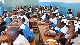 Niños recibiendo comida en la escuela en Puerto Príncipe