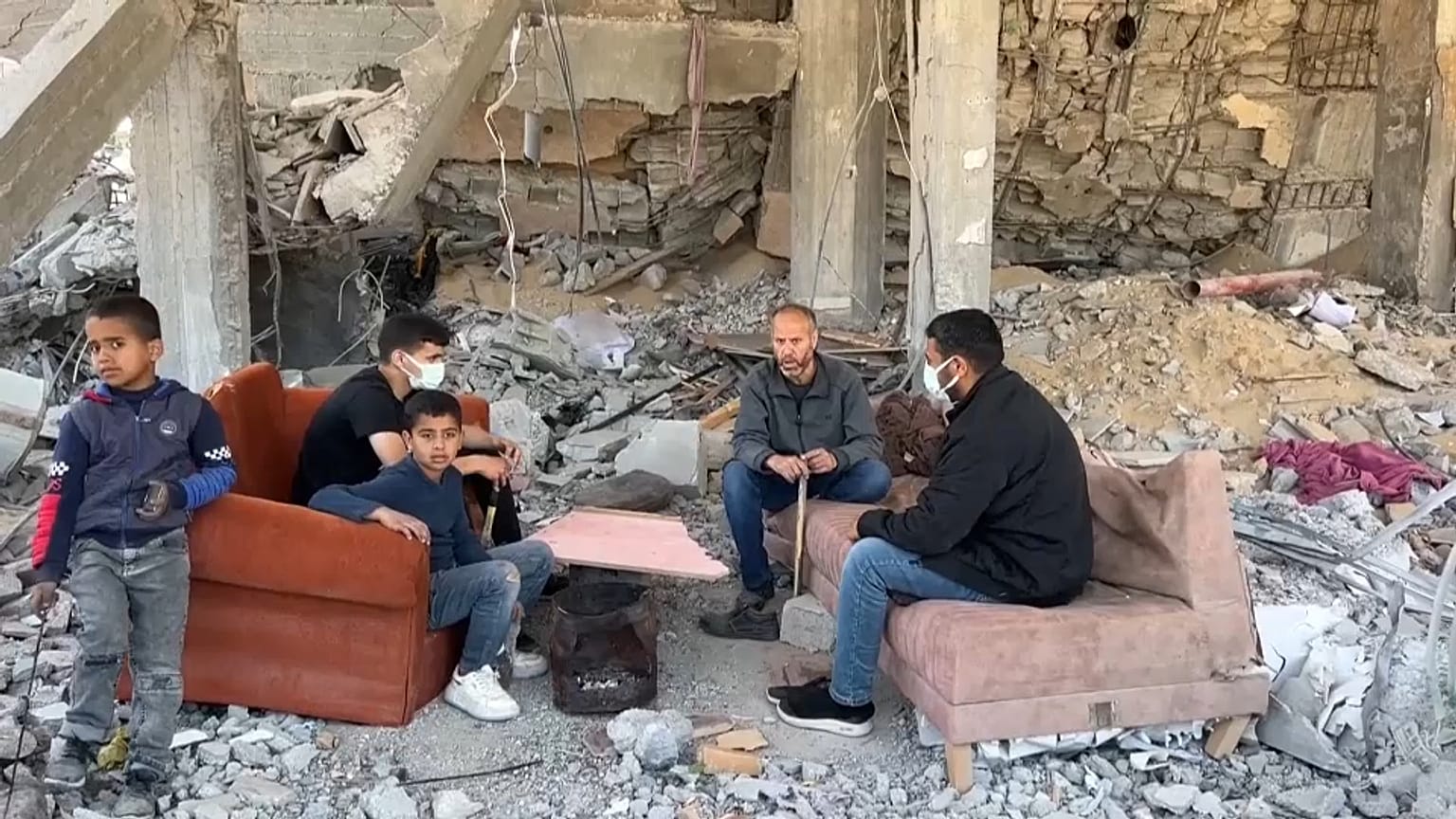 عائلة فلسطينية تجلس على أنقاض منزلها المدمر في خان يونس 
