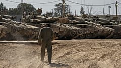 Israeli soldiers work on tanks at a staging ground near the border with the Gaza Strip, in southern Israel, Thursday, April 11, 2024.