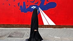 Una mujer pasa junto a un nuevo mural contra Estados Unidos en la pared de la antigua embajada estadounidense en Teherán, 2019. 