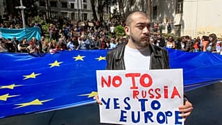A man stands in front of protestors with a giant EU flag outside the parliament building in Tbilisi, Georgia, on Monday, April 15, 2024.