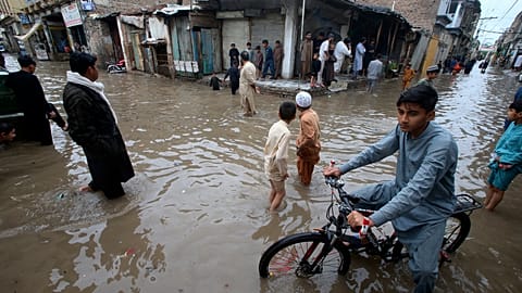 Youngsters wade through a flooded street caused by heavy rain in Peshawar, Pakistan in April 