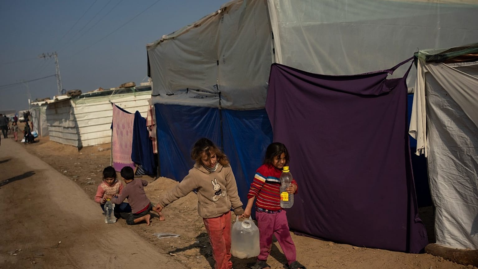 أطفال فلسطينيون يحملون المياه في مخيم المواصي، غزة