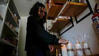 Una mujer enciende velas en su tienda después de un corte de energía programado ordenado por el Ministerio de Energía, en Quito, Ecuador, el martes 16 de abril de 2024.