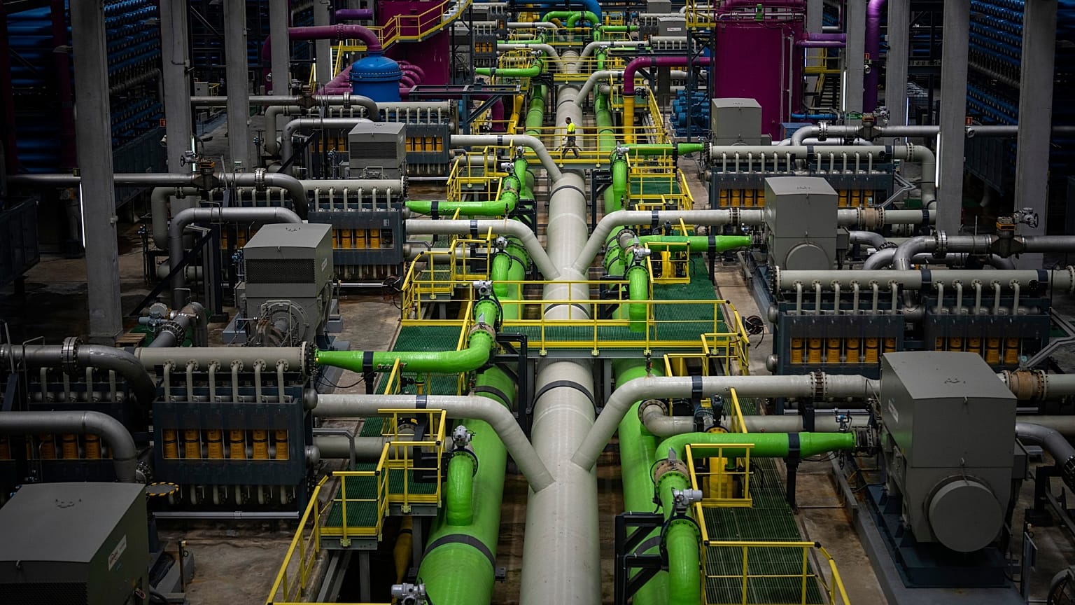 Un trabajador camina sobre la tubería que transporta el agua de mar a los filtros de la mayor planta desalinizadora de agua potable de Europa, situada en Barcelona.
