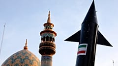 نموذج لصاروخ يحمله متظاهرون إيرانيون، بينما تظهر مئذنة وقبة مسجد في الخلفية خلال تجمع مناهض لإسرائيل في ساحة فلسطين في طهران، إيران، الاثنين 15 أبريل 2024.