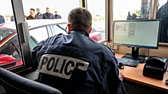 Французский полицейский проверяет паспорта и транспортные средства у входа в туннель под Ла-Маншем в Кале на севере Франции