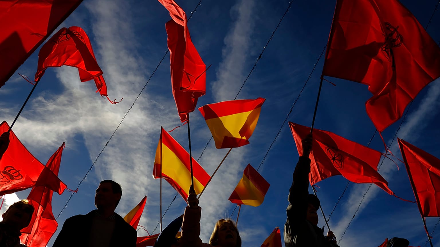 Manifestantes agitam bandeiras espanholas e de Navarra enquanto protestam contra a amnistia na praça Plaza del Castillo, em Pamplona, norte de Espanha, sábado, 18 de novembro de 2023. 