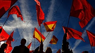 Manifestantes agitam bandeiras espanholas e de Navarra enquanto protestam contra a amnistia na praça Plaza del Castillo, em Pamplona, norte de Espanha, sábado, 18 de novembro de 2023.