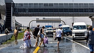 People walk through floodwater caused by heavy rain while waiting for transportation on Sheikh Zayed Road highway in Dubai.