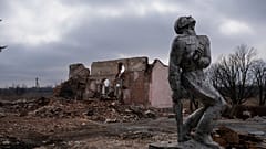 Sowjetisches Denkmal, das den Soldaten des Zweiten Weltkriegs gewidmet ist, vor einem zerstörten Kulturhaus in der Nähe von  Awdijiwka. 21. März 2024