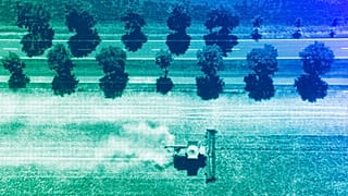 A farmer harvests a grain field near Wernigerode, Germany, August 2023