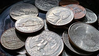 Los cuartos, monedas de cinco, diez y centavos se colocan en un tazón el jueves 31 de marzo de 2022 en Tigard, Oregon. 