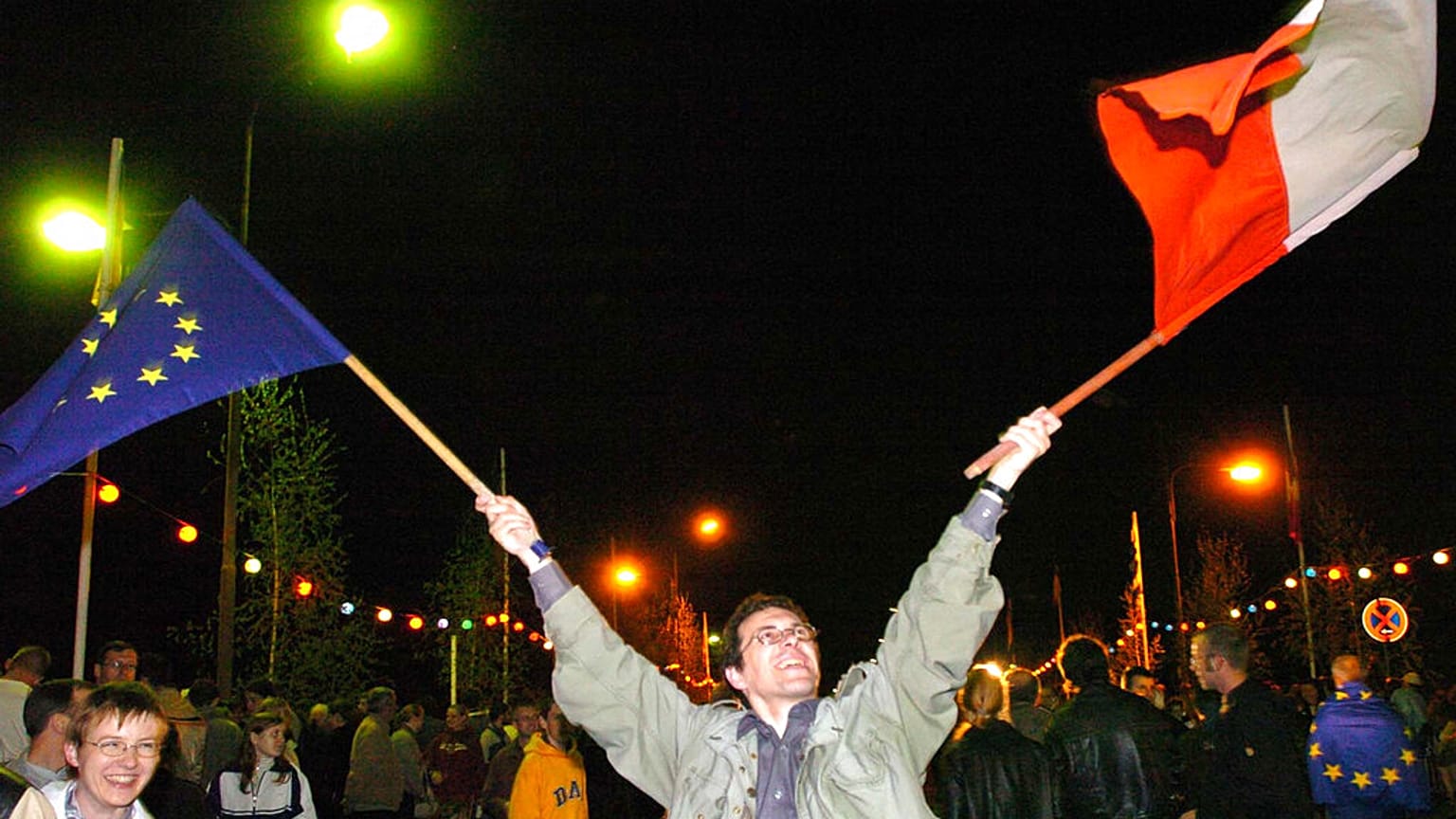 Piotr Zubrzycki waves a Polish, right, and a EU flag to celebrate the EU enlargement 
