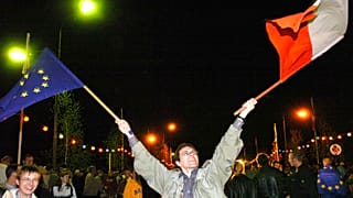 Piotr Zubrzycki waves a Polish, right, and a EU flag to celebrate the EU enlargement 