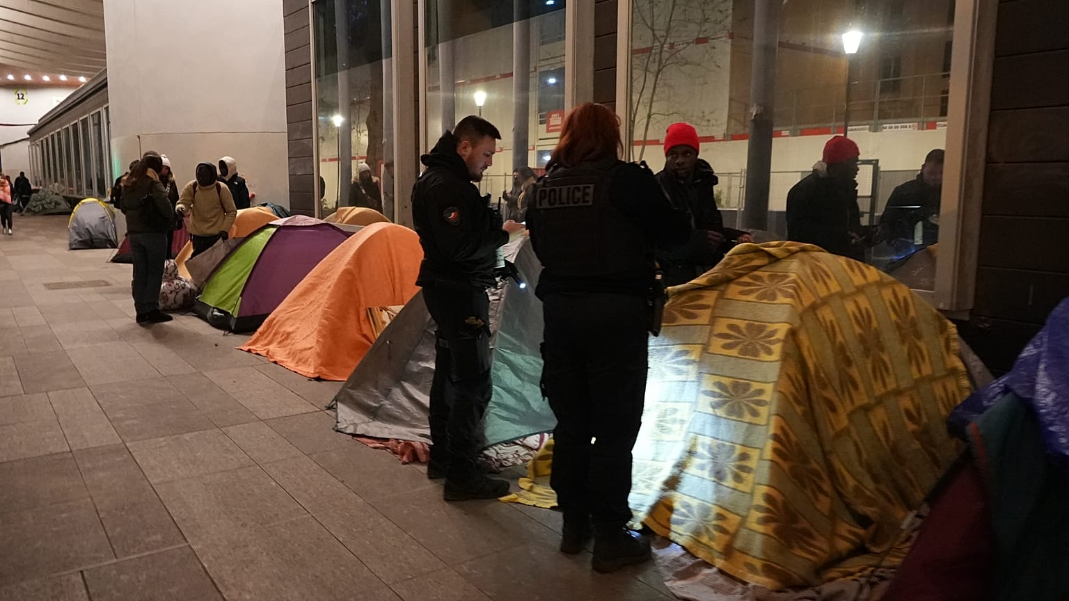 Police officers check a migrant in a makeshift camp, early Tuesday, April 23, 2024 in Paris.