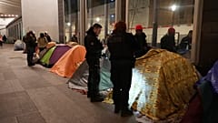 Police officers check a migrant in a makeshift camp, early Tuesday, April 23, 2024 in Paris.