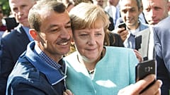 Almanya Başbakanı Angela Merkel, Berlin'e gelen mülteciler için bir tesiste bir mülteci ile selfie çekmek için poz veriyor. 9 Eylül 2015