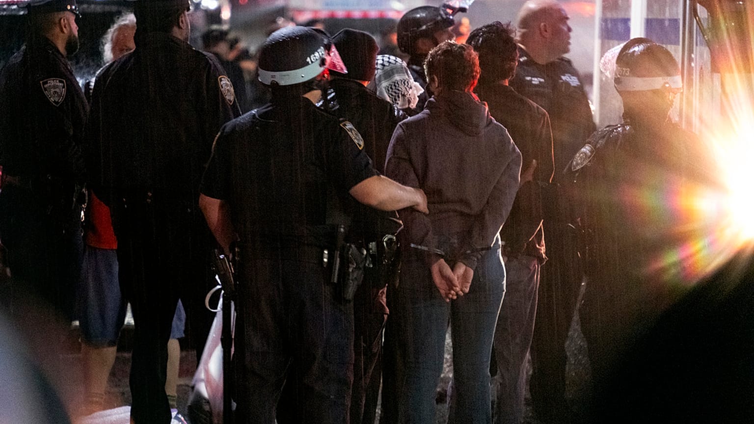 As light rain falls, New York City police officers take people into custody near the Columbia University campus in New York, Tuesday, April 30, 2024
