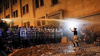 أحد المتظاهرين يشير إلى محاولته إيقاف شرطة مكافحة الشغب خلال احتجاج للمعارضة ضد «القانون الروسي» (AP Photo/Zurab Tsertsvadze)