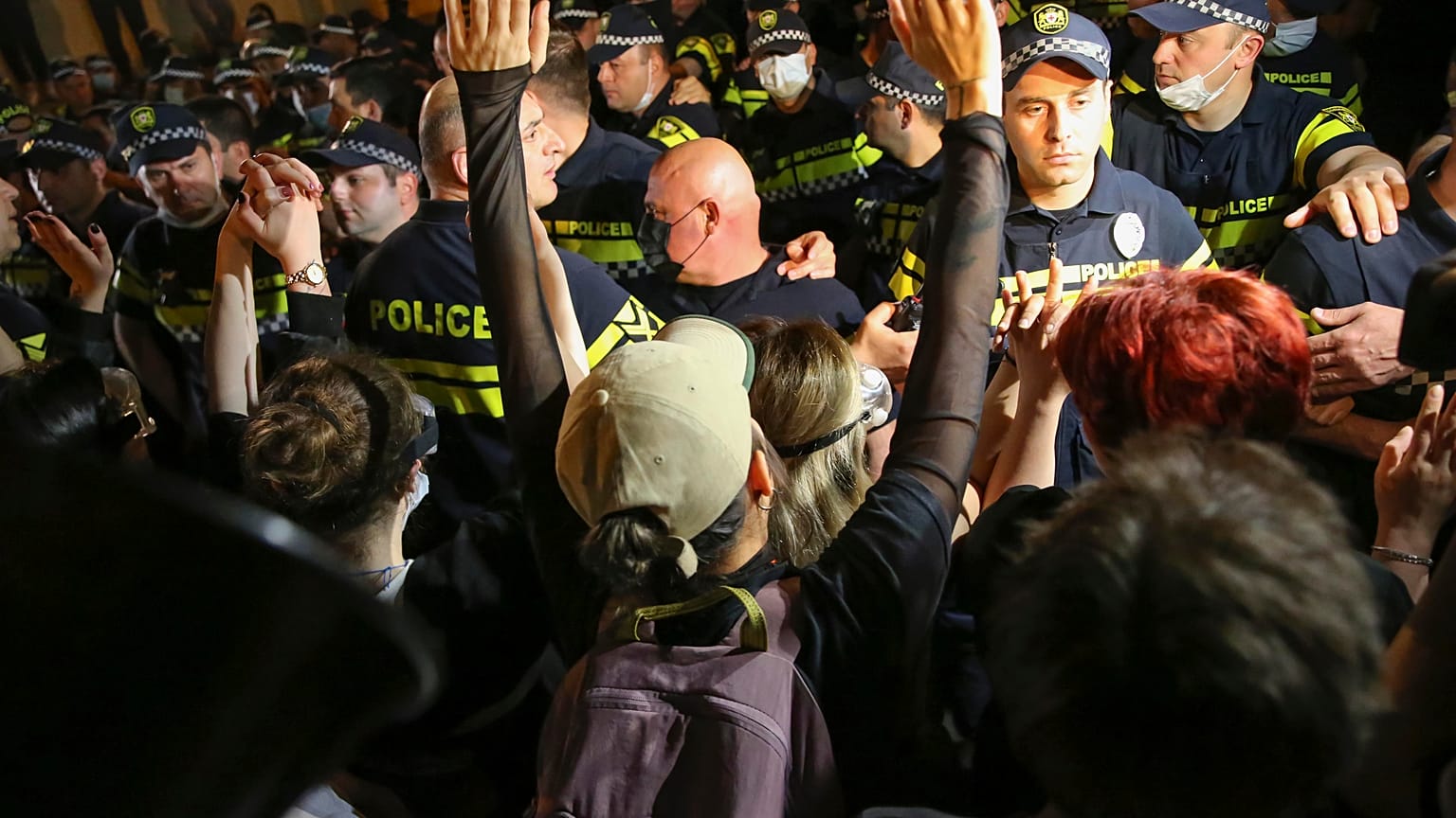 Um manifestante gesticula enquanto argumenta com a polícia durante um protesto contra a 'lei russa' perto do edifício do Parlamento em Tbilisi, 1 de maio de 2024