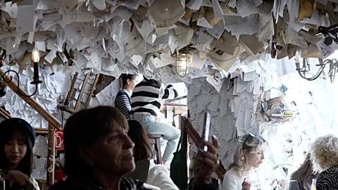 Tourist filming notes on the walls in "The For Sale" pub